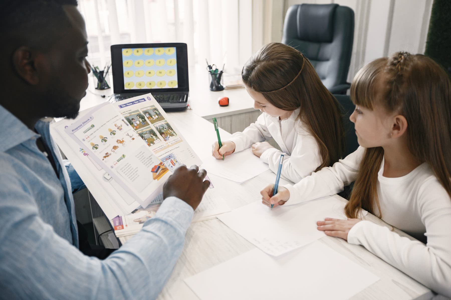 A teacher guiding two students through their classroom work.